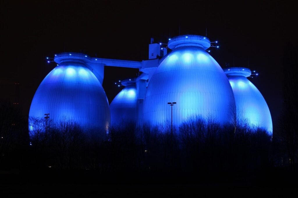 Blau beleuchtete Faultürme der Bottroper Kläranlage bei Nacht, regionaler Hinweis auf Übersetzungsdienstleistungen von Nachtigal Services.