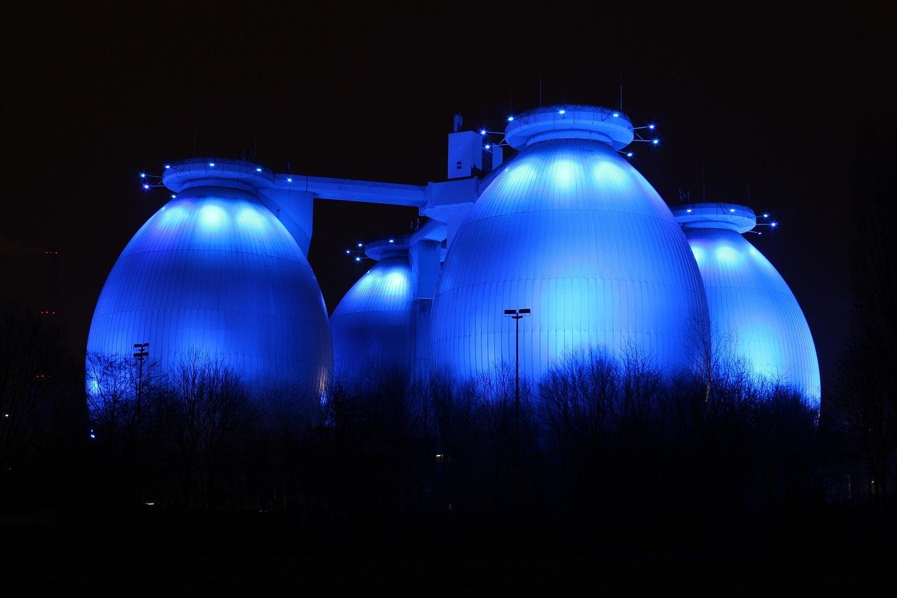 Blau beleuchtete Faultürme der Bottroper Kläranlage bei Nacht als regionaler Hinweis auf Übersetzungsdienstleistungen