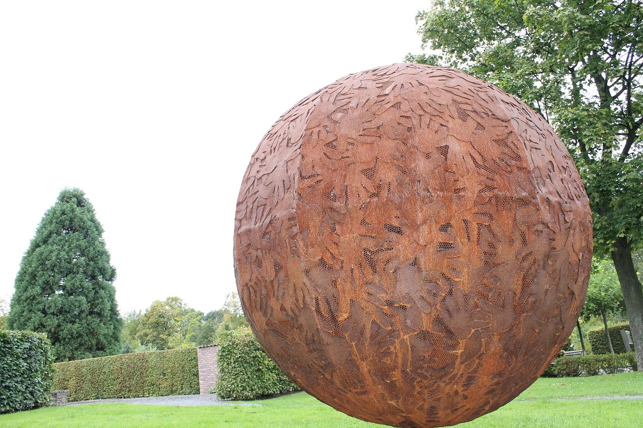 Kunstskulptur im Grugapark Essen mit großer Metallkugel im Grünen als regionaler Bezug zu Übersetzungsdienstleistungen