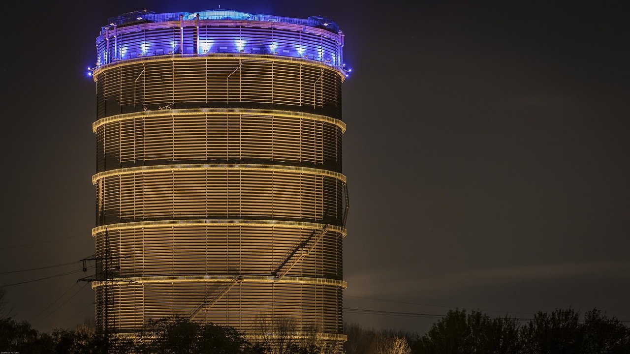 Beleuchteter Gasometer Oberhausen bei Nacht als Wahrzeichen der Stadt und regionaler Bezug zu beglaubigten Übersetzungen von Nachtigal Services