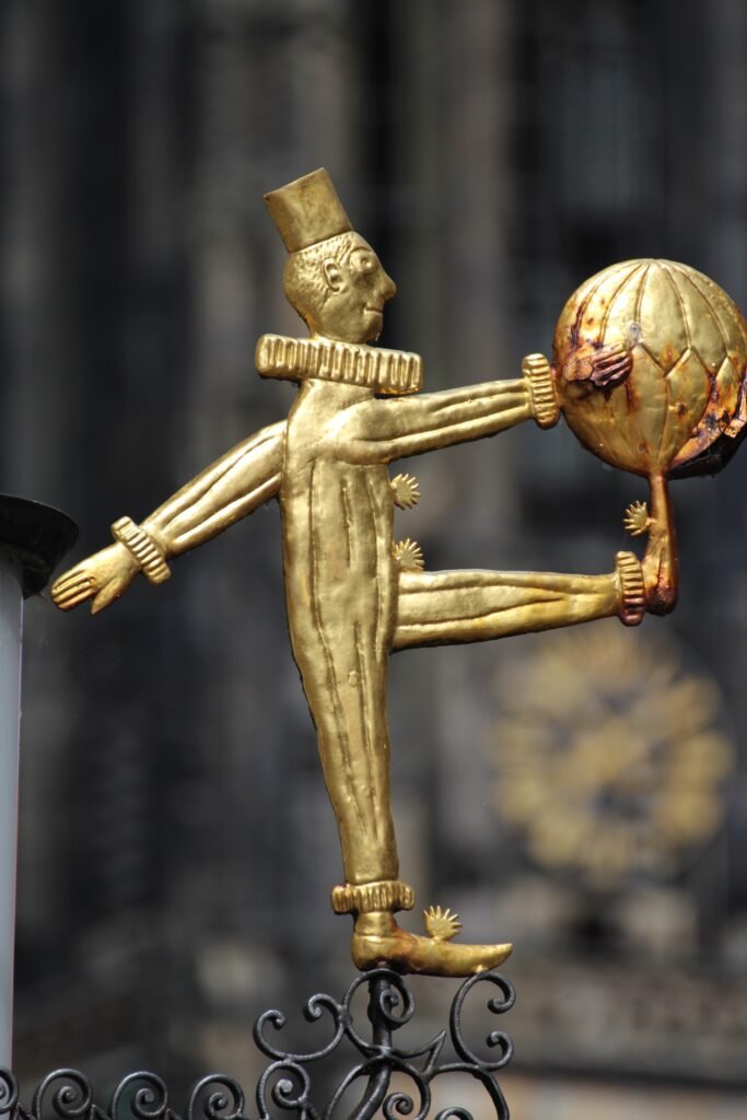 Goldene Figur mit Globus auf historischer Fassade in Münster – Detail einer Skulptur im Stadtzentrum.